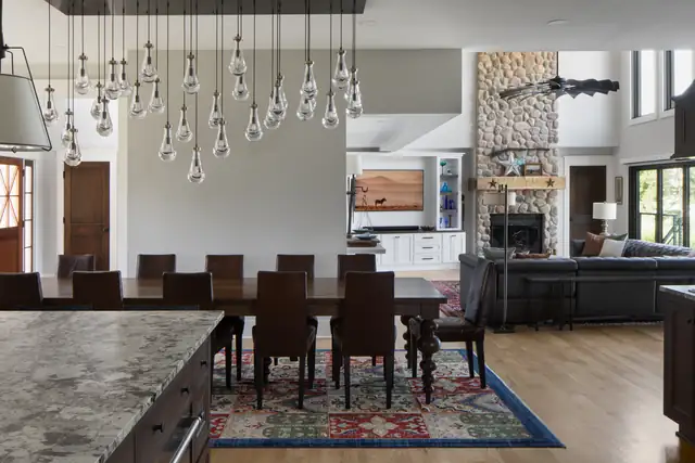 Americana whole-home remodel with open dining room, cluster pendant lighting and a fieldstone fireplace in the family room
