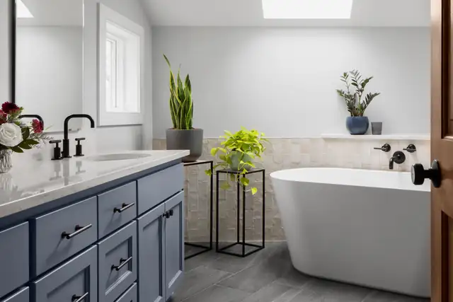 Thrush Lane primary bathroom with navy double vanity, black faucets, freestanding soaking tub and skylight