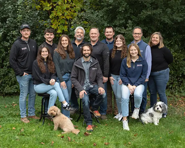 The Wade Design and Construction team gathered outdoors on the grass with two dogs